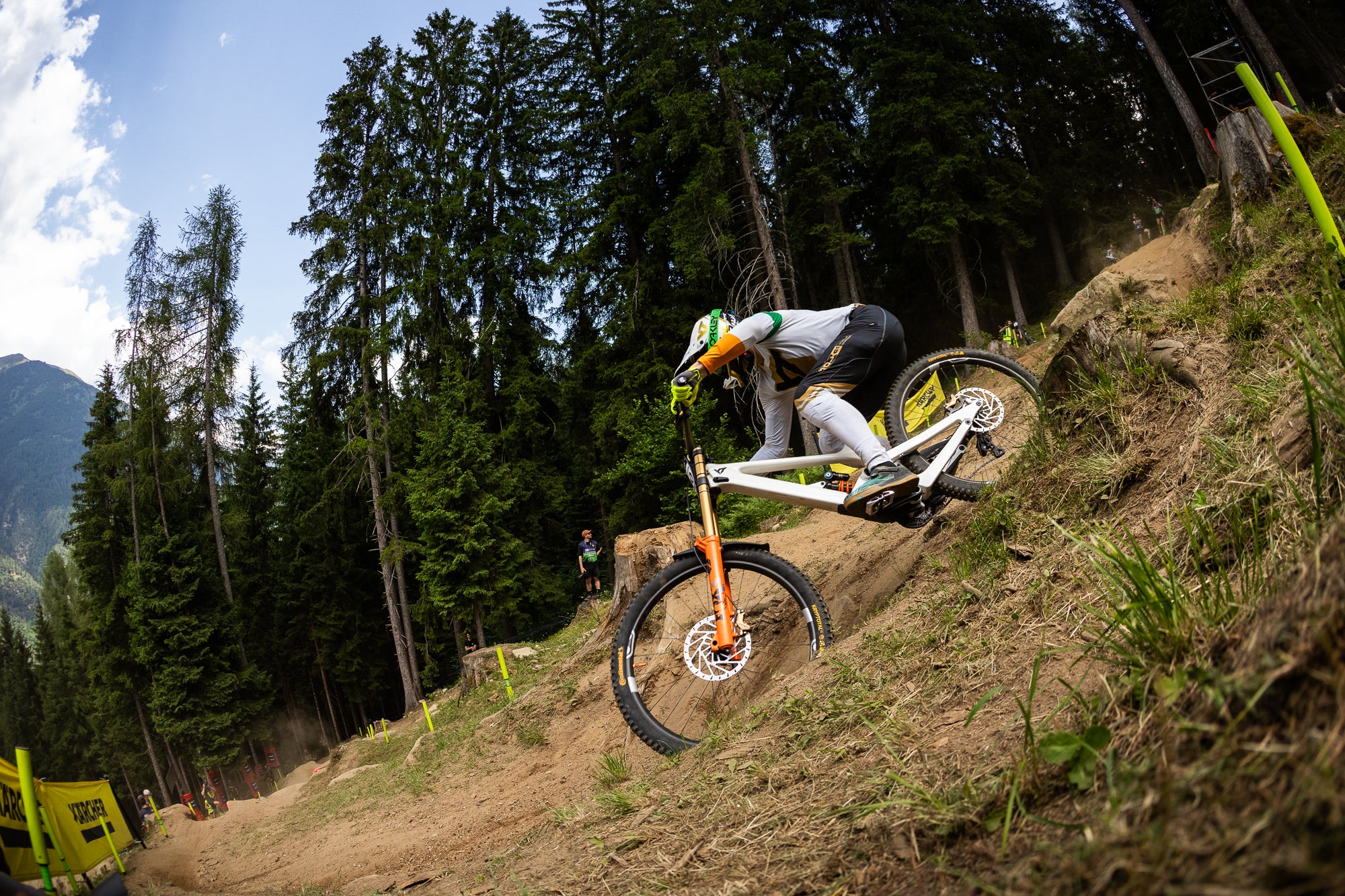 Person riding a mountain bike on a trail with trees and mountains in the background
