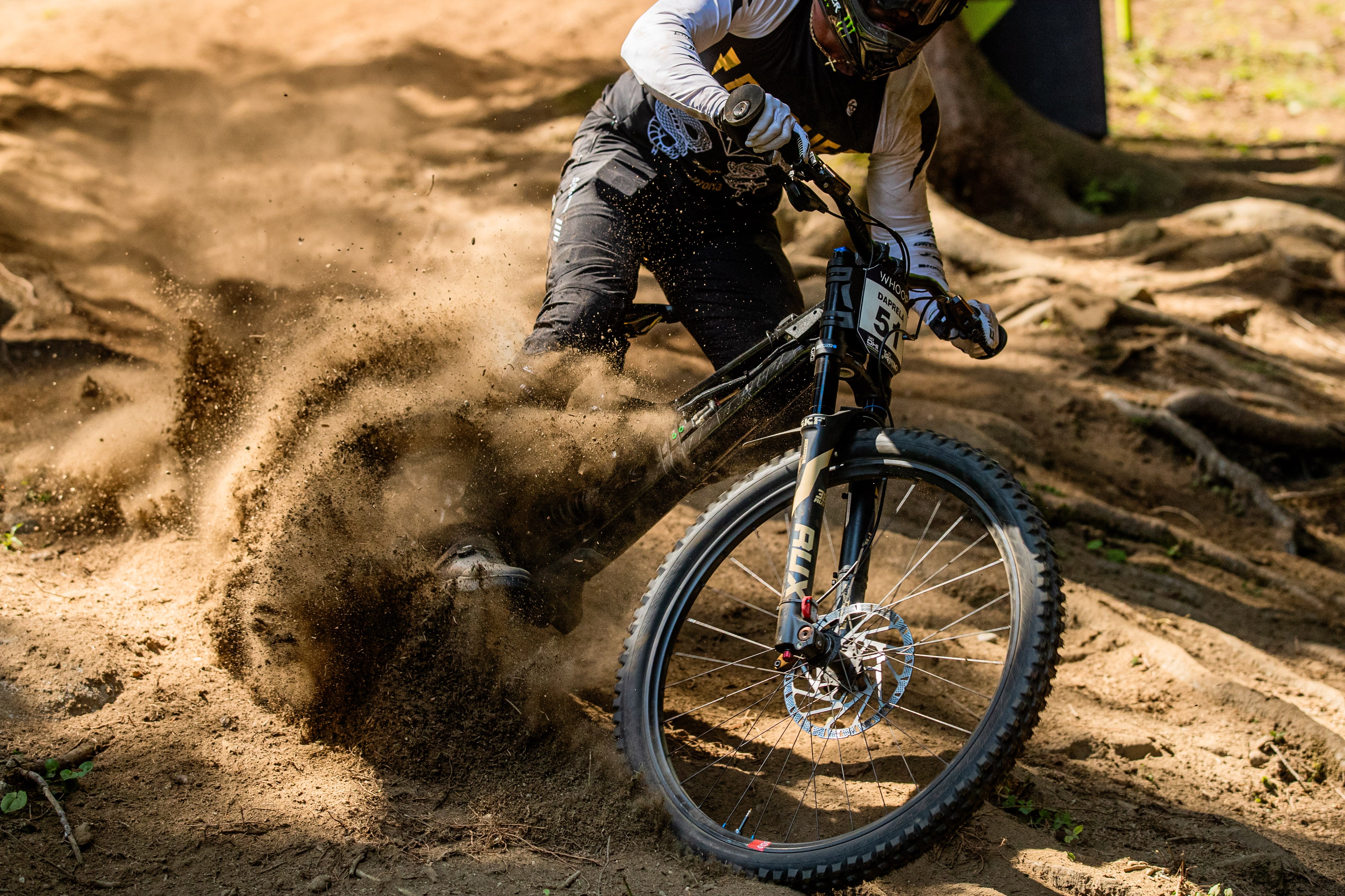 Downhill biker mid turn with dirt spraying off the tires