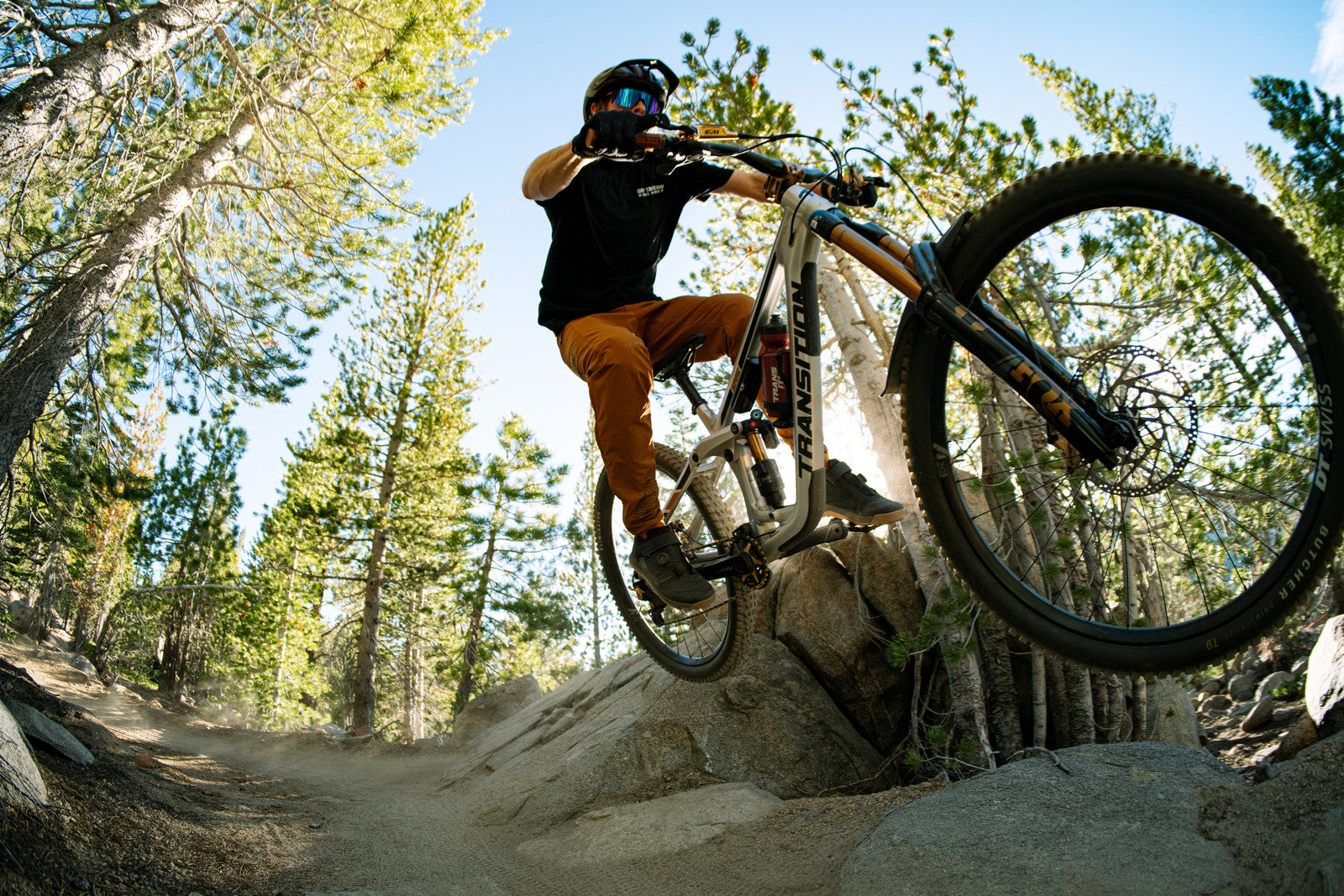 person riding a mtb with TRP components in the forest jumping off a rock curb