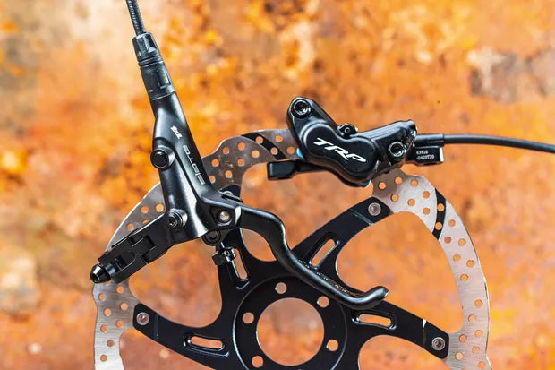 Shows TRP Slate T4 EVO mountain bike hydraulic disc brake system with carbon fiber components for enduro riding