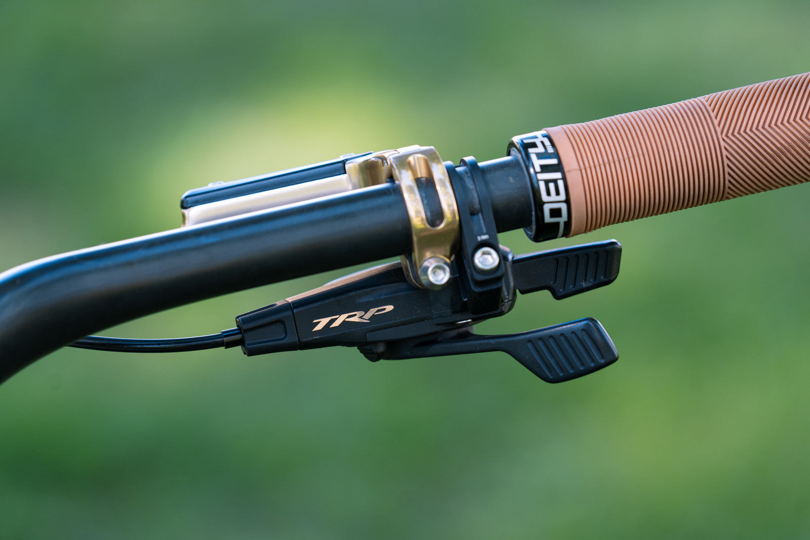 close-up of TRP shifter in gold mounted on a MTB handle bar