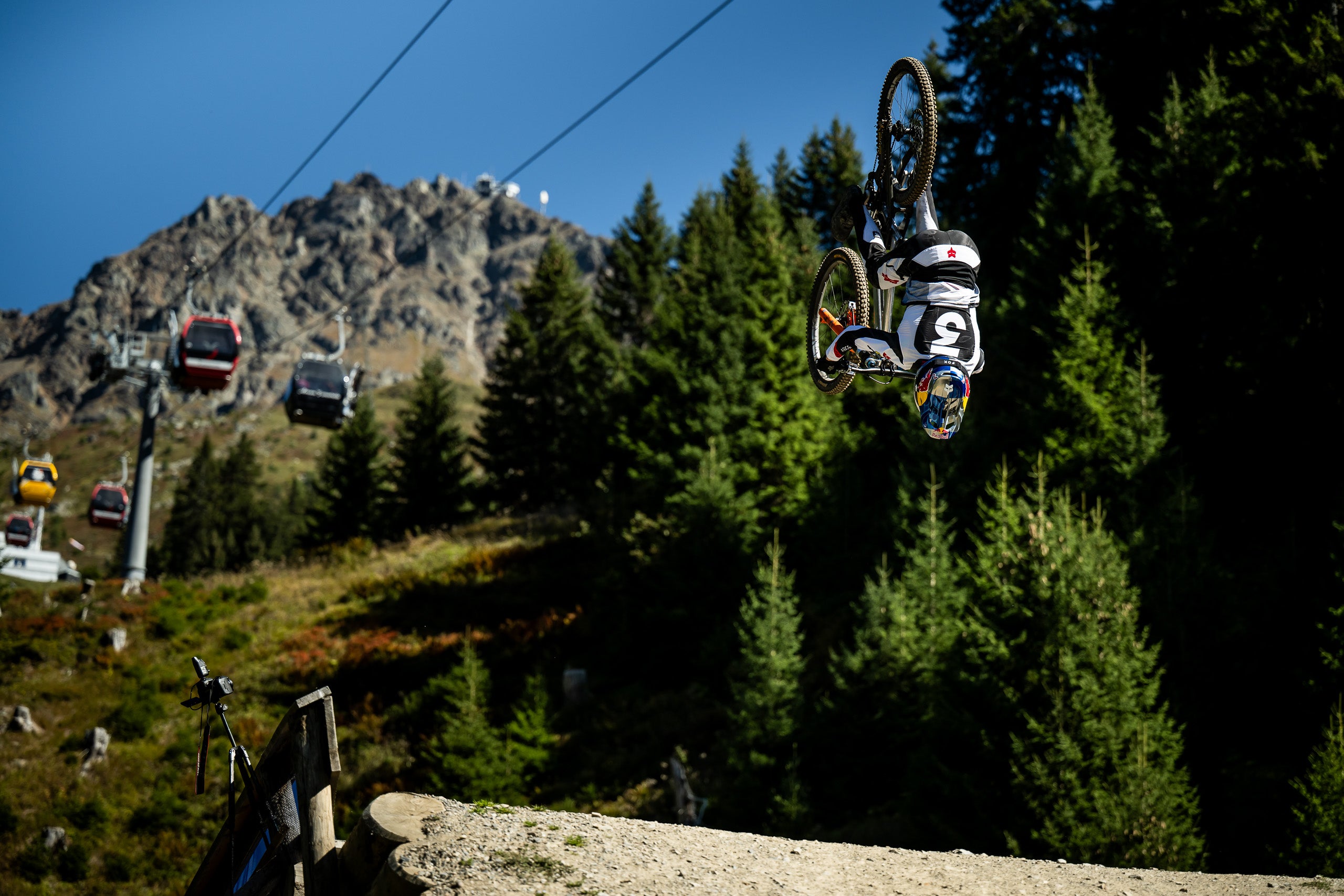 Mountain biker making a backflip next to Gondola lift system in Lenzerheide with mountain and trees in the background