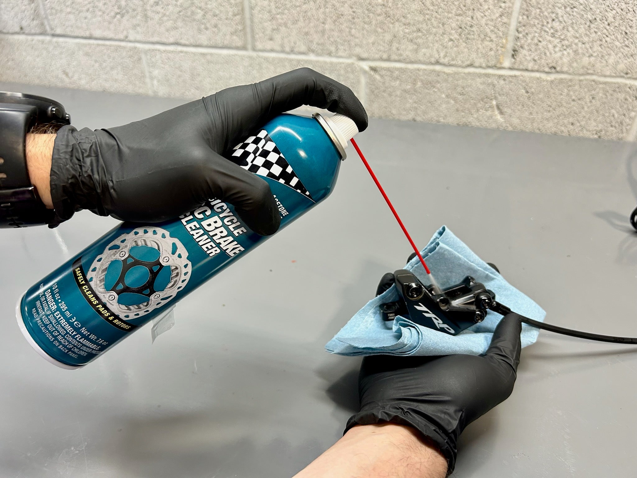 hands that hold a break cleaner cleaning a TRP bike caliper