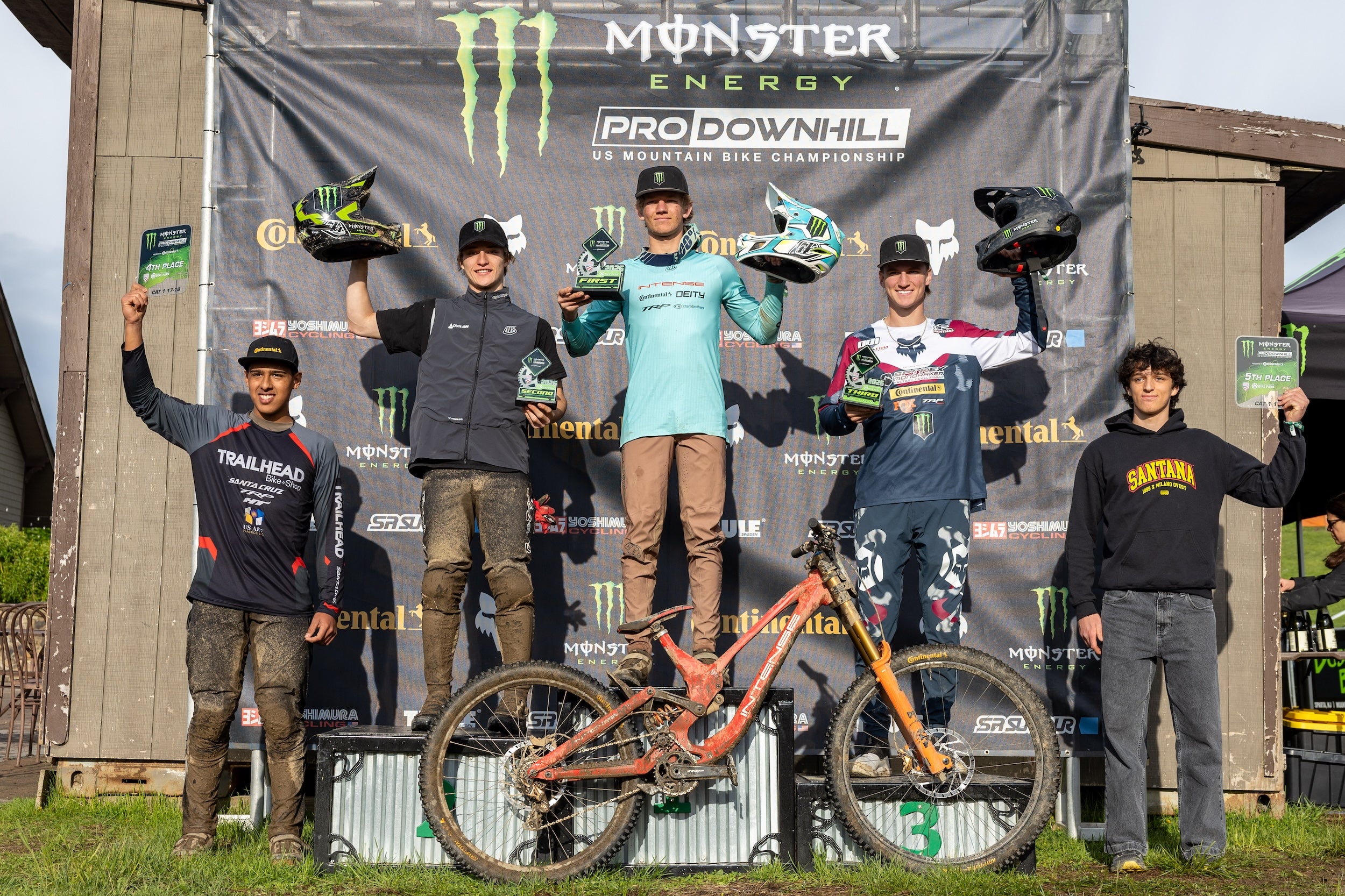 Winners of a mountain bike championship event standing on a podium with Monster Energy branding.