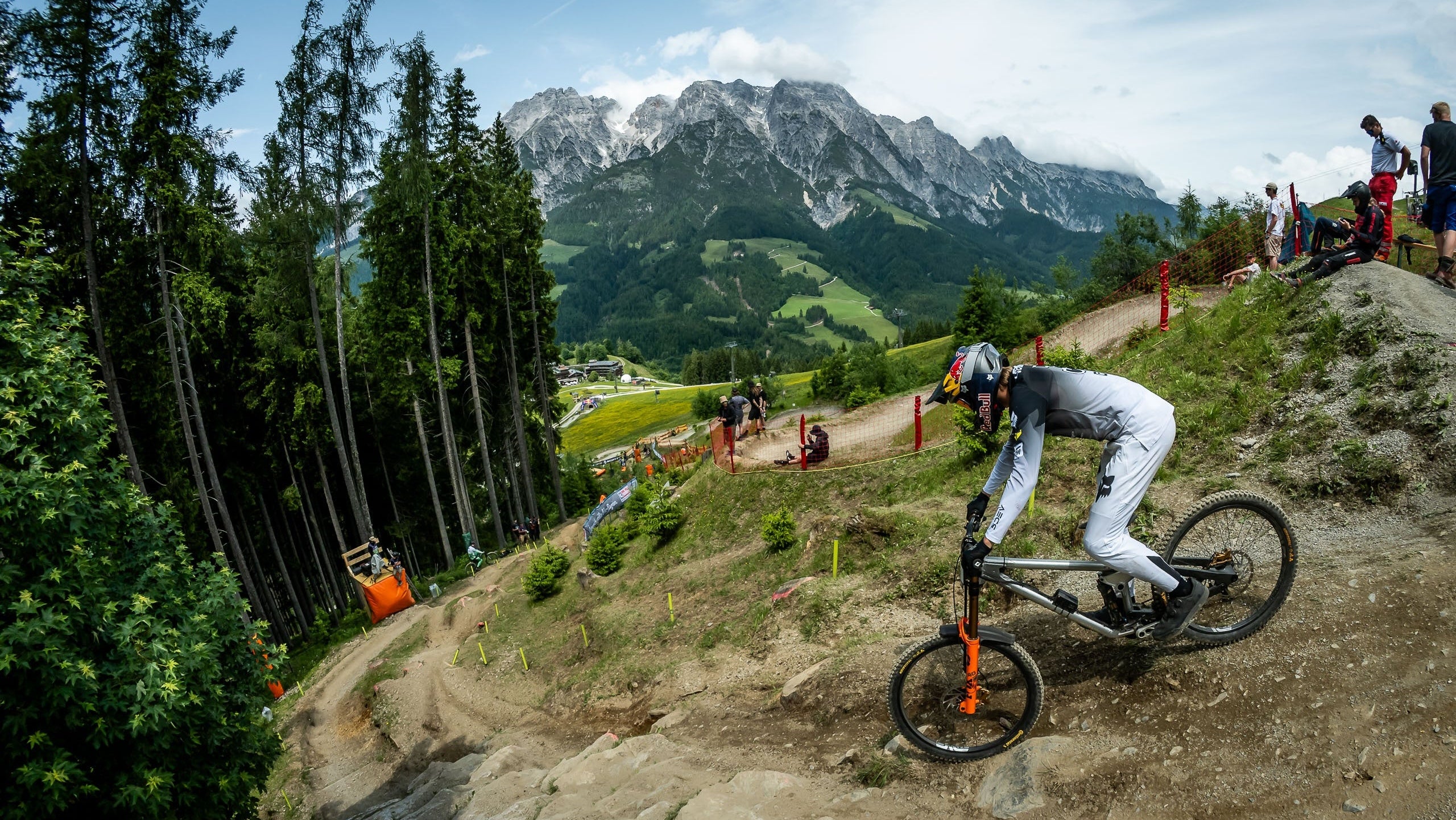 Person riding a bike on a mountain trail with mountains in the background during a competition in st leongang